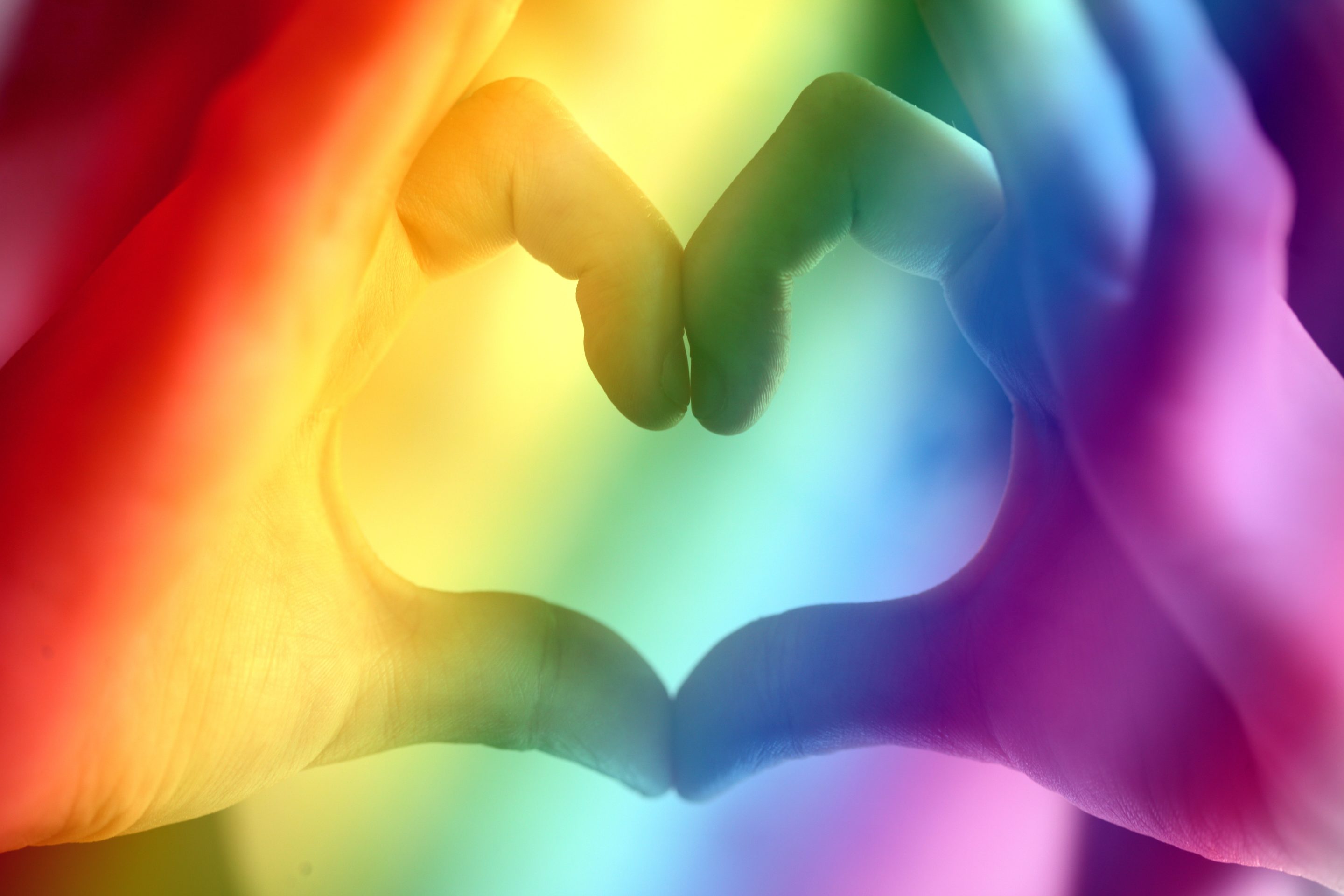 Pride flag with hands making a heart.