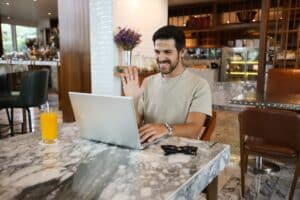 a man sitting at a table using a laptop computer -- Photo by Ling App on Unsplash