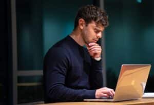 man in black long sleeve shirt sitting in front of macbook -- Photo by Christian Velitchkov on Unsplash