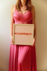 Woman holds a sign reading "accountability." -- Photo by Ava Sol on Unsplash
