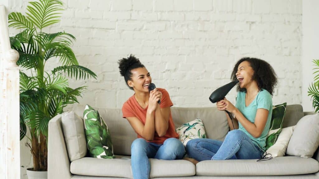 Two women singing into a microphone and hairdryer -- Photo by Vitaly Gariev on Unsplash