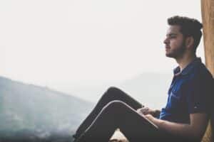 a man sitting on a ledge with a mountain in the background -- Photo by Harsh Gupta on Unsplash