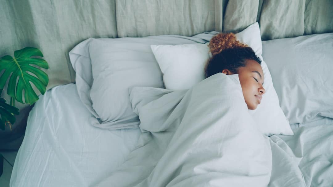 A young woman sleeping peacefully in a white bed. -- Photo by Vitaly Gariev on Unsplash