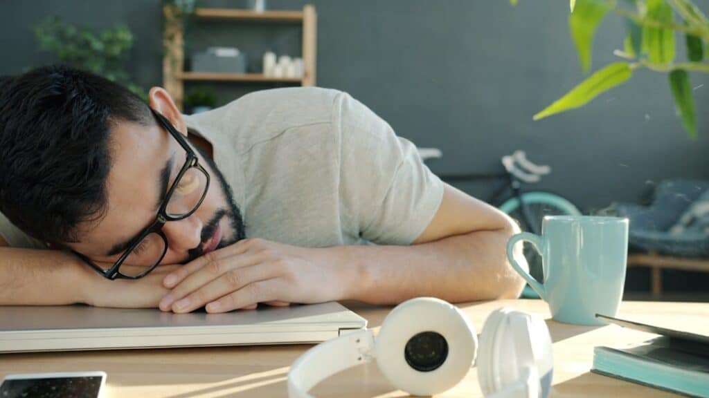 Man sleeping at desk with headphones and coffee. -- Photo by Vitaly Gariev on Unsplash
