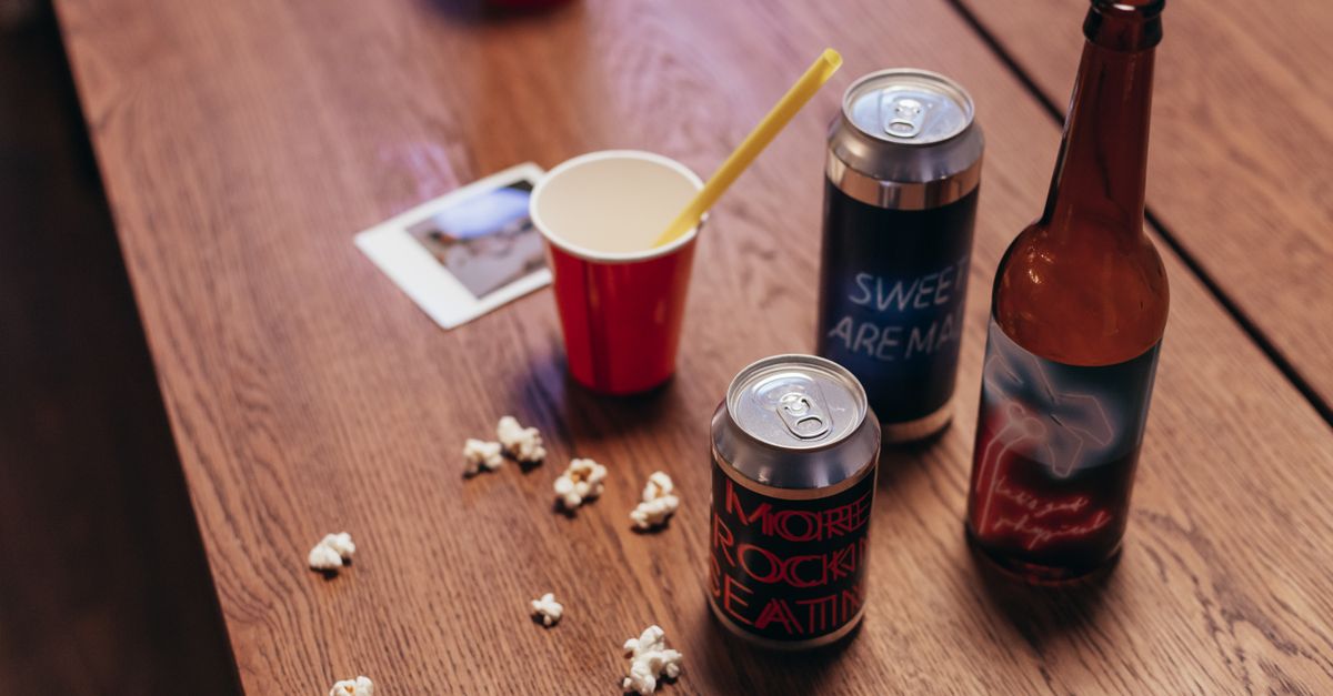 Close-up of assorted drinks and snacks on a wooden table, evoking a casual gathering vibe.
