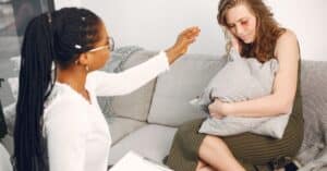 A therapist provides support to a woman experiencing emotional distress in a therapy session.