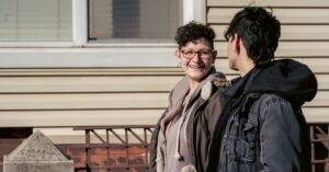 Happy adult lesbian couple strolling on sunny autumn street and chatting cheerfully while looking at each other with smile