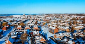 Panoramic aerial view capturing a snow-covered coastal cityscape on a bright winter day.