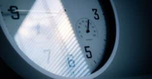 A close-up of a wall clock showing time and humidity, reflecting light and shadows.