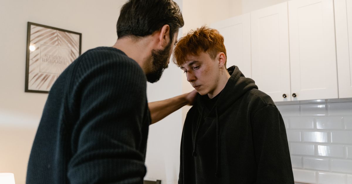 A comforting scene showing empathy between two men in a modern kitchen setting.