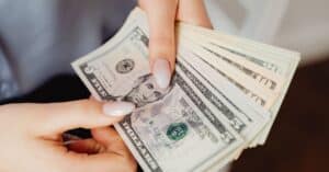 Hands count US dollar bills, showcasing finance and cash handling concepts.