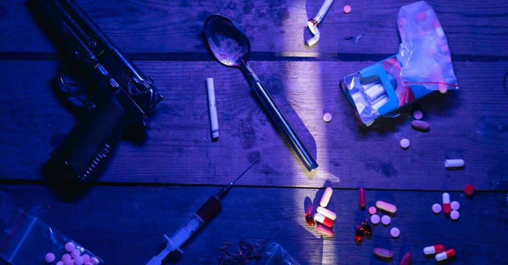 Intriguing still life image depicting pills, a gun, and syringe under dramatic lighting.