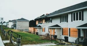 Boarded-up suburban homes with visible fire damage and neglect.