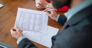 Close-up of businesspeople reviewing documents at a meeting.