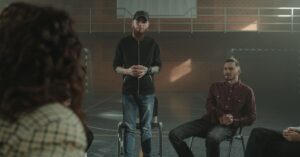 A group therapy session taking place indoors with diverse participants seated in a circle.