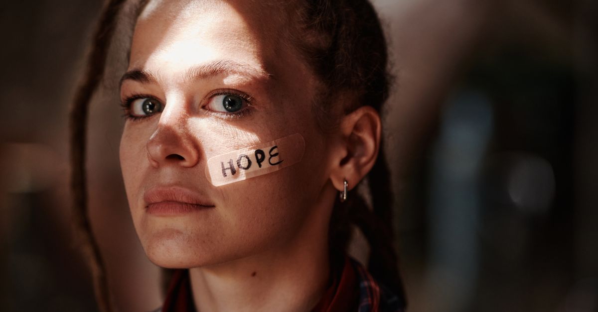 Close-up portrait of a woman with 'hope' written on a band aid. Depicts resilience and optimism.