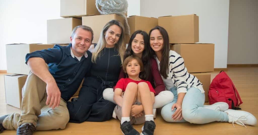 A joyful family sitting together with moving boxes in their new home.