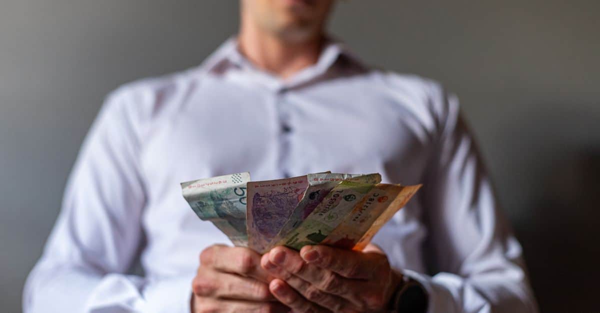 Man holding Argentine Peso banknotes in Buenos Aires, Argentina, illustrating currency concept.