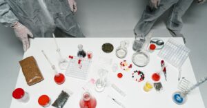 Top view of a laboratory setup with various scientific tools and substances, featuring researchers in lab coats.