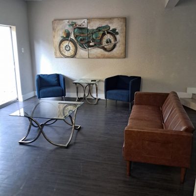 Two-man suite sober living in Austin with modern furniture, glass coffee table, and leather sofa