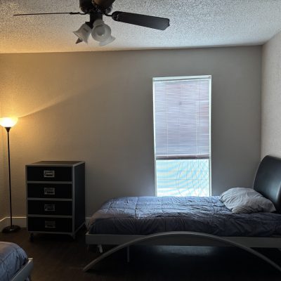 Affordable two-bedroom men’s sober living in Austin with twin beds, dresser, and soft lighting